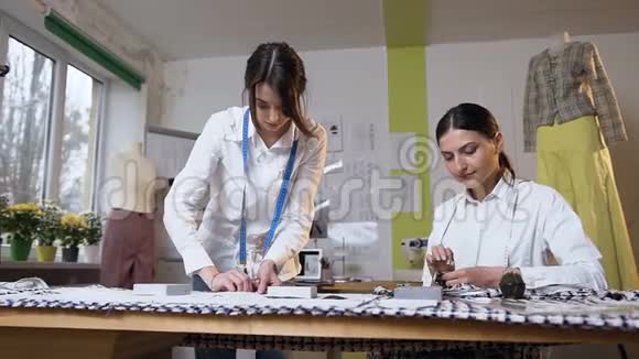 两个女裁缝在缝纫工作室缝制一块布视频的预览图
