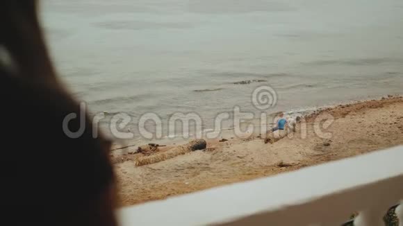 独自一人的女人早上在阳台上喝咖啡或茶有蓝色的海景孩子们在海边玩耍视频的预览图