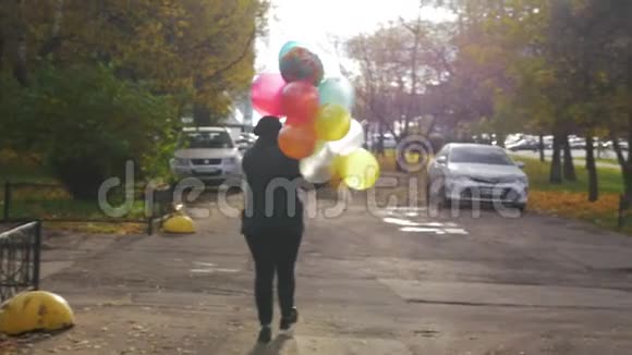一个女人带着五颜六色的气球在街上缓慢地走着视频的预览图