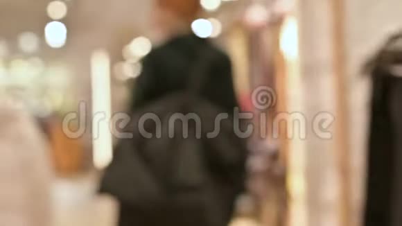 从后面的女孩穿着毛衣和帽子购物的视野穿过一家服装店现场摄像机视频的预览图