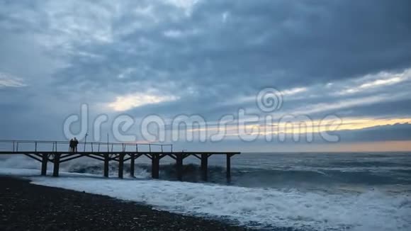 日落时分席洛瓦夫妇在码头海上漫步暴风巨浪泡沫视频的预览图