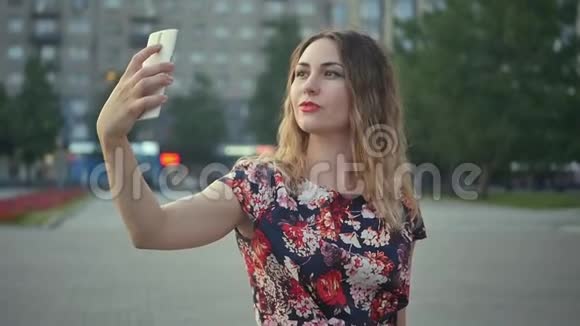 有魅力的女孩拍一个自拍视频卷曲的女人在度假时有一个视频流城市的远距离关系视频的预览图
