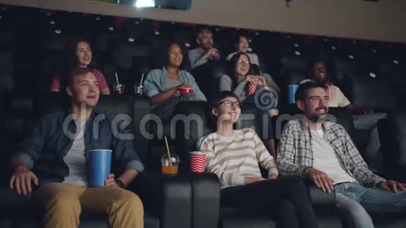 多种族的年轻人在电影院看电影时笑视频的预览图