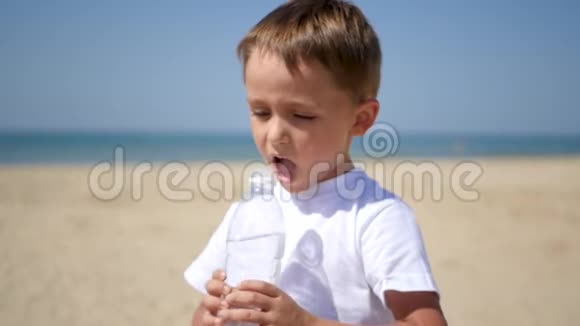 一个小孩在沙滩上喝透明塑料瓶里的水视频的预览图