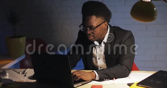 年轻的商人深夜在办公室里用笔记本电脑工作他读了好消息完成了工作视频的预览图