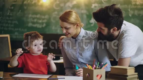 父母和他们的儿子在学校教室里画一块绿色的黑板回学校去孩子在上课有趣搞笑视频的预览图