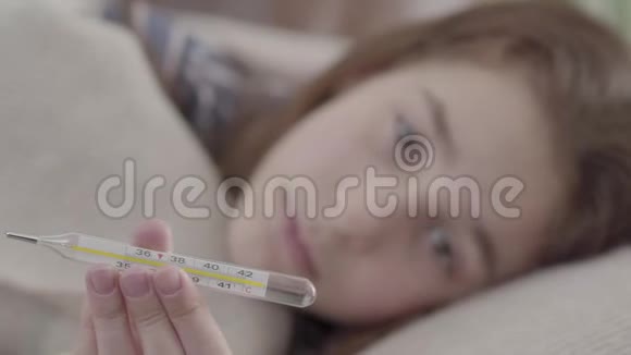 把生病的女孩躺在床上在相机里显示一个温度计生病孩子的概念医学和健康视频的预览图