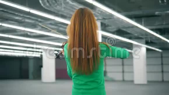 红发女子在空厅里熟练地拉小提琴视频的预览图