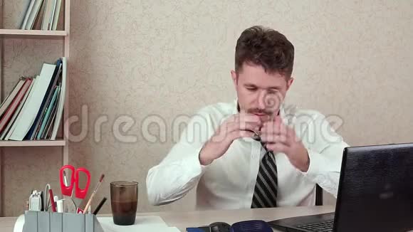男人办公室经理头痛他坐在笔记本电脑前喝咖啡视频的预览图