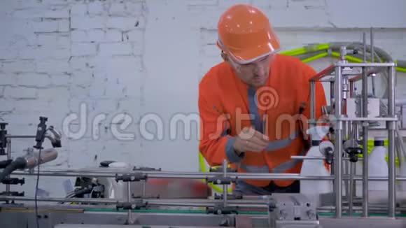 工厂工人戴安全帽穿工作服在自动皮带线上检查家用化学品的质量生产视频的预览图