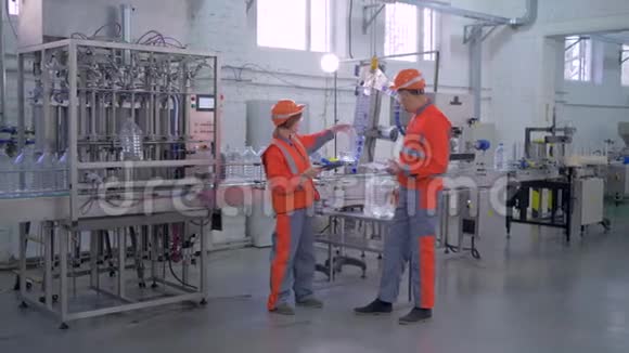 工厂的质量生产控制专家男女进入安全帽和工作服输送线附近装瓶视频的预览图