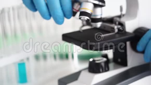 男性化验员戴蓝色防护手套使用显微镜视频的预览图