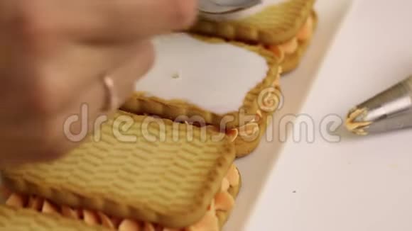 一个女人正在用饼干和奶油准备糕点用牛奶淋上饼干软化视频的预览图