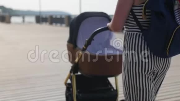 一位年轻的母亲带着一辆电车在木板路上散步并在电话中拍下了大海的照片中弹视频的预览图