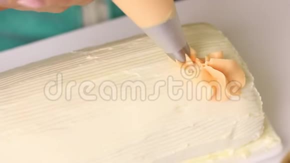 一个女人用奶油装饰一个饼干卷上面覆盖着奶油使用糕点袋视频的预览图