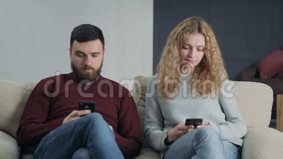 一对夫妇坐在床上不说话在智能手机上打字视频的预览图
