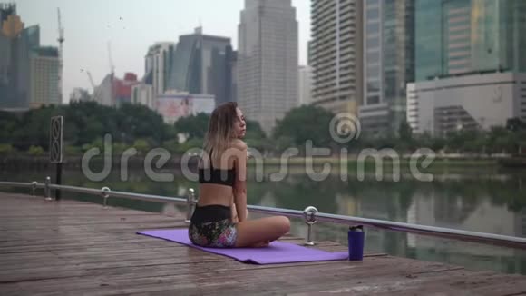 一位留着长发的年轻女子在城市公园的健身地毯上工作后享受着痛苦的时光视频的预览图