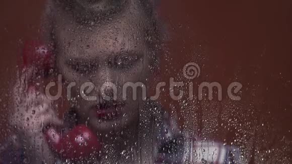 伤心哭泣的女人正在潮湿的窗户后面打电话视频的预览图