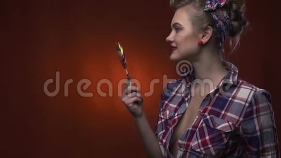 漂亮的金发女孩正在舔她的棒棒糖微笑着慢动作视频的预览图