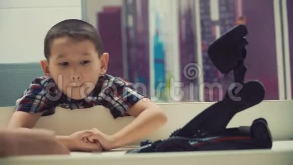 一个亚洲人模样的小男孩专心听着兴致勃勃地看着小机器人拿起一支笔视频的预览图