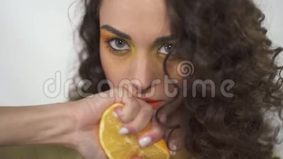 这幅画是一个美丽的女孩抬起眼睛嘴唇附近拿着一个橘子挤压着创造出流动的果汁慢慢视频的预览图