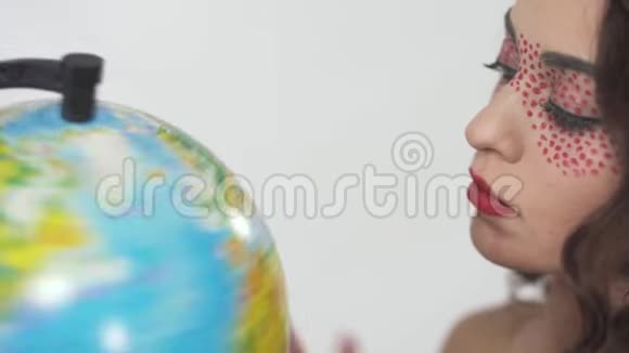 特写肖像年轻美丽的卷发女孩与明亮的化妆研究地球选择一个国家视频的预览图
