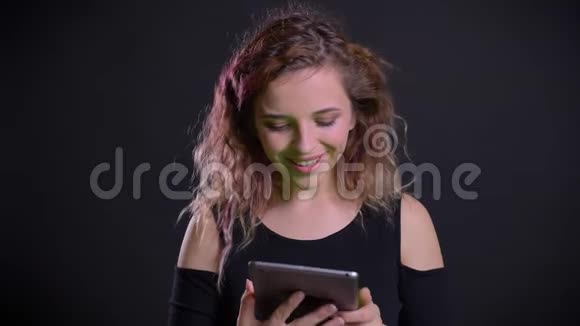 在平板电脑里观看粉色头发的快乐白种人女孩的肖像受到了震撼并在镜头中展示视频的预览图
