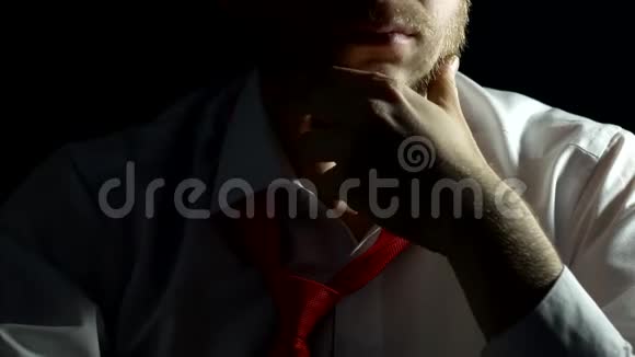 一个穿着白色衬衫的人胡子刮过摸过胡子很紧张黑色背景特写商人视频的预览图
