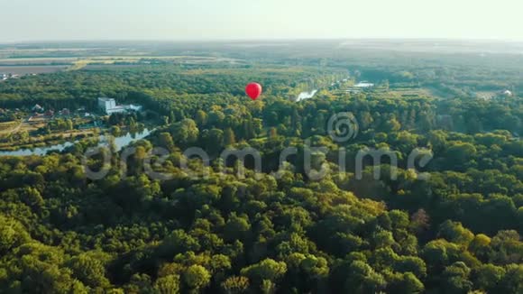空中观看红色热气球飞过树木日落夏景视频的预览图