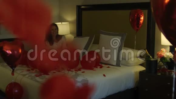 快乐的新娘坐在床上拿着气球视频的预览图