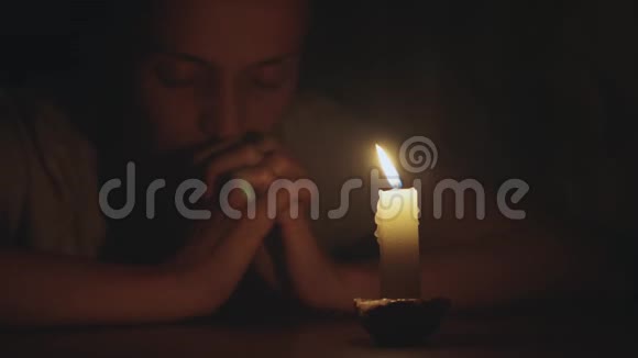 年轻女子正在祈祷蜡烛的前面特写视频的预览图