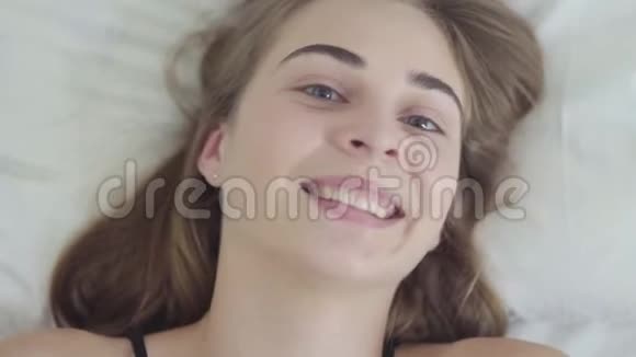 一个年轻漂亮的女人早上躺在床上用毯子遮住她的脸视频的预览图