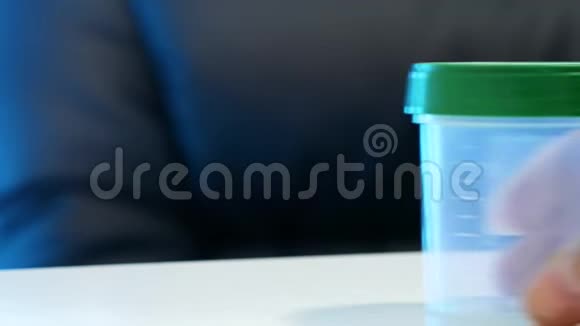一个男人把一个空的精子容器放在桌子上精液分析人工授精概念视频的预览图
