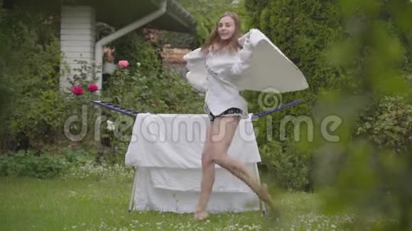 漂亮开朗的年轻女人在后院唱歌跳舞很有趣同时做家务和亚麻布洗衣日视频的预览图