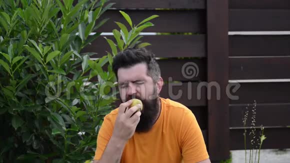 留胡子的人在户外吃桃子快乐的人在后院微笑和休息有胡子的家伙享受花园里的水果蔬菜视频的预览图
