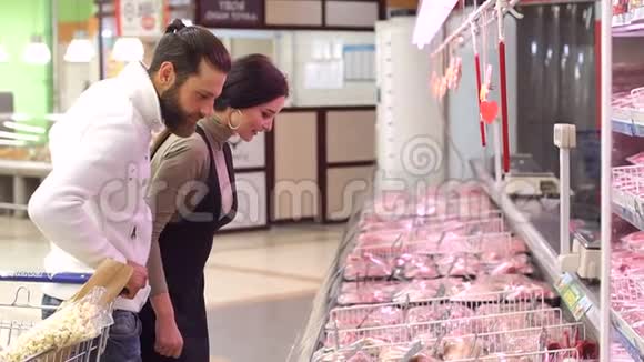 积极微笑的家庭夫妇选择冷冻肉在食品店视频的预览图