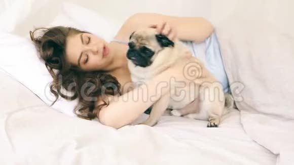 放松的早晨和狗在床上拥抱录像片段年轻的白种人女人玩宠物狗视频的预览图