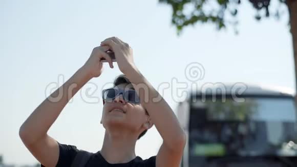 一个戴太阳镜的年轻人在智能手机上为博客拍摄视频视频的预览图