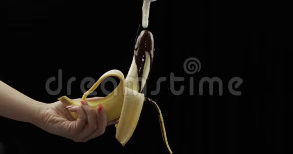 拿着香蕉和融化的巧克力把鲜奶油挤在水果上面视频的预览图
