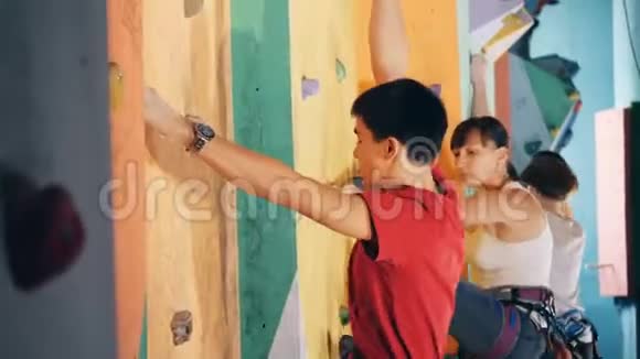 在健身房里雄性和雌性正在攀爬一堵巨石墙视频的预览图