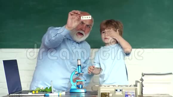 友好的孩子男孩与老成熟的老师在教室附近的黑板桌祖父和孙子祖父和祖父视频的预览图