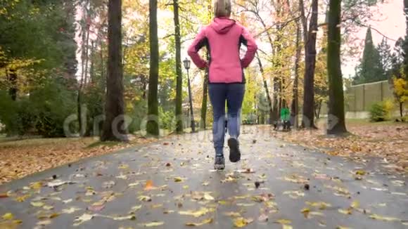 运动的小女孩雨后在秋天公园跑步后视镜视频的预览图