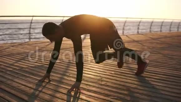 一个年轻的运动员在户外做俯卧撑的图片在大海或海洋前面的木制泡沫健身和视频的预览图