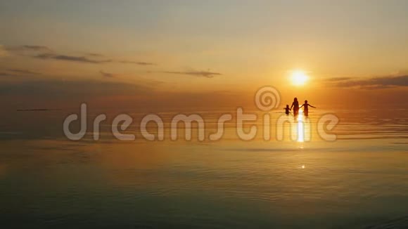 日落时分母亲带着两个孩子在海里大笑视频的预览图