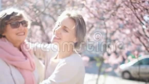美丽的阳光明媚的春天母女肖像两个女人在阳光下拥抱和欢笑视频的预览图