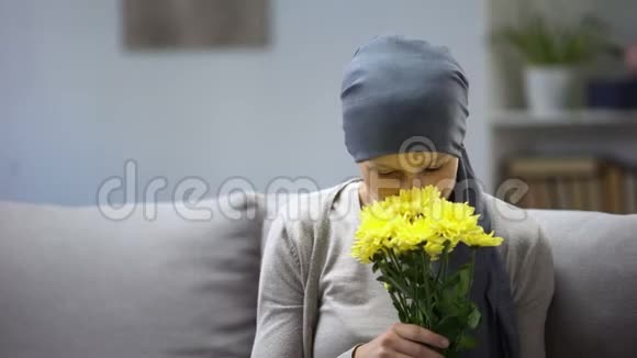癌症后的康复戴头巾的女人闻着鲜花享受生活视频的预览图