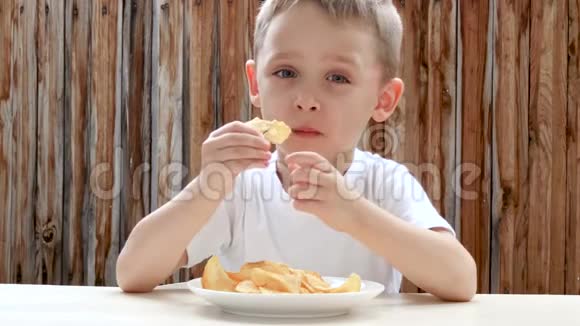 一个孩子喜欢吃薯片而坐在一张桌子上背景是一堵木墙视频的预览图
