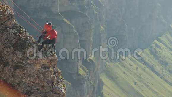 三个登山者用绳子从岩石上卸下重物视频的预览图