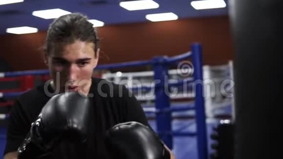 确定的跆拳道击中拳击梨一个愤怒的拳击手戴着黑色手套在拳击袋里打了一拳在健身房锻炼视频的预览图