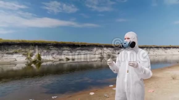 穿着防护服和体外呼吸器的人站在干河旁边的海滩上视频的预览图